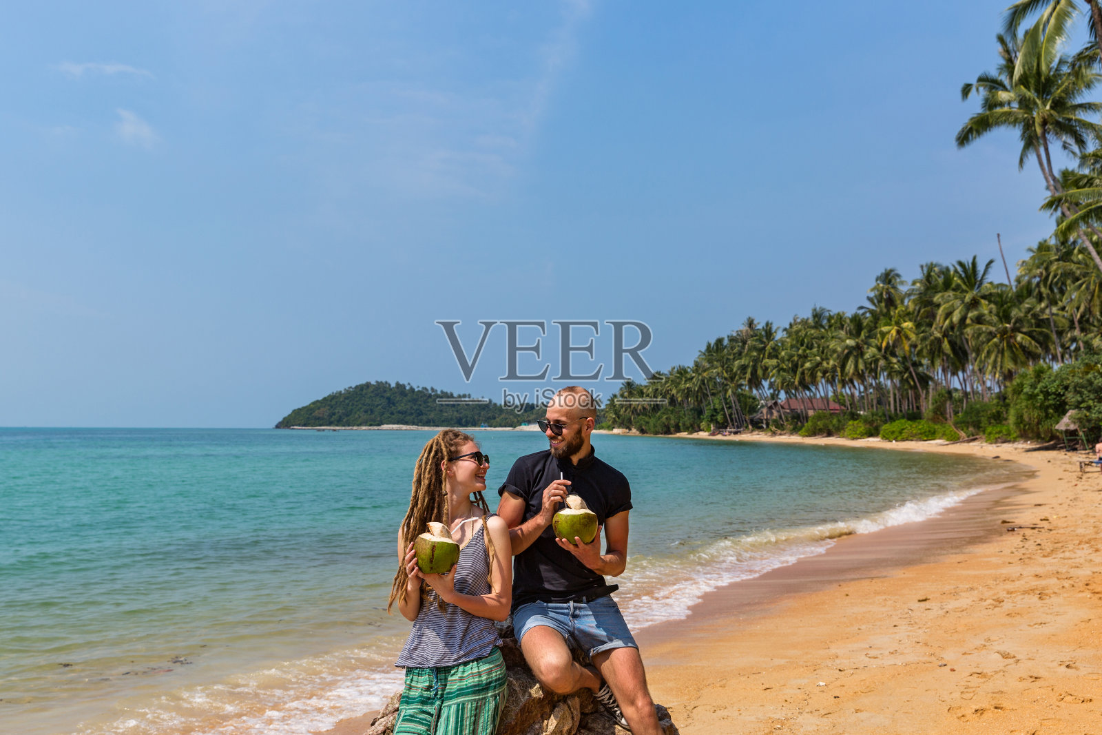 一对情侣在海滩上喝椰子汁照片摄影图片