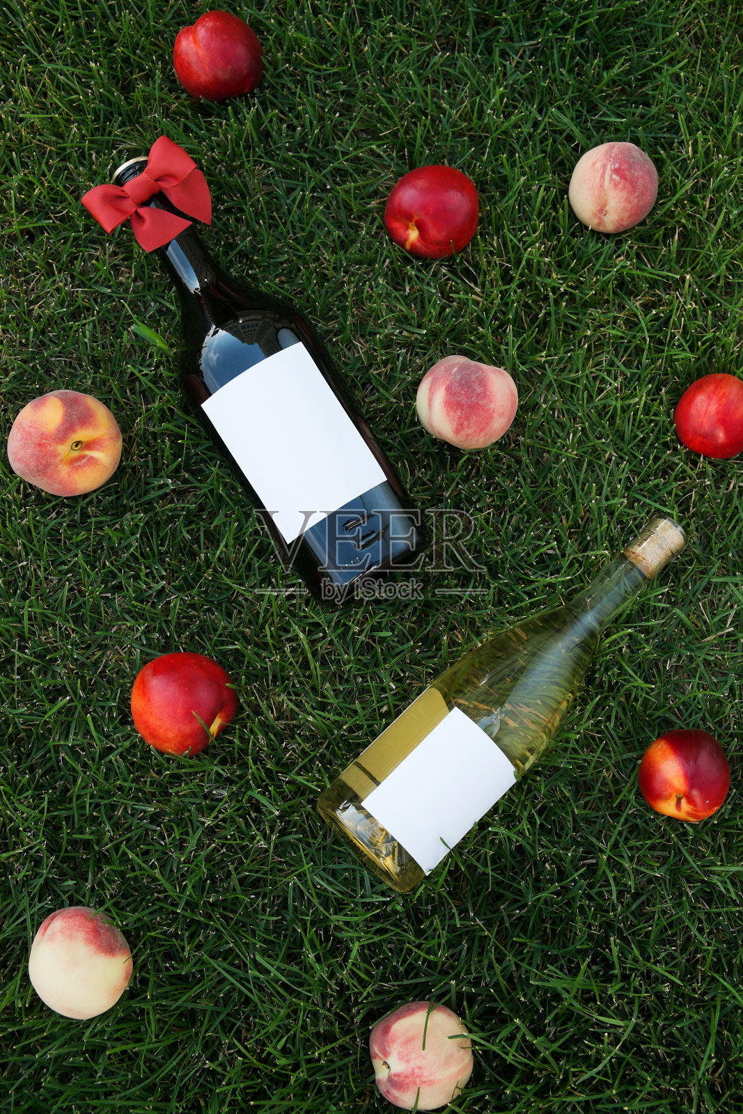 两瓶酒和草地上的桃子照片摄影图片