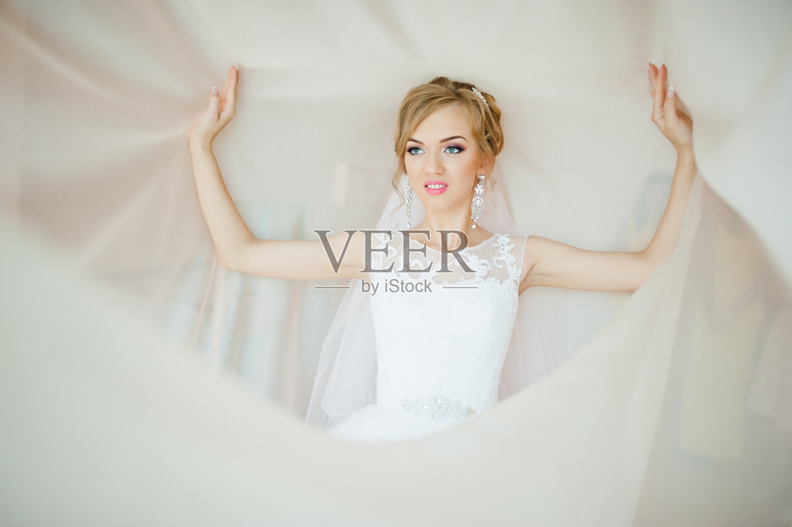 窗帘上温柔的金发新娘，温柔的姿势照片摄影图片