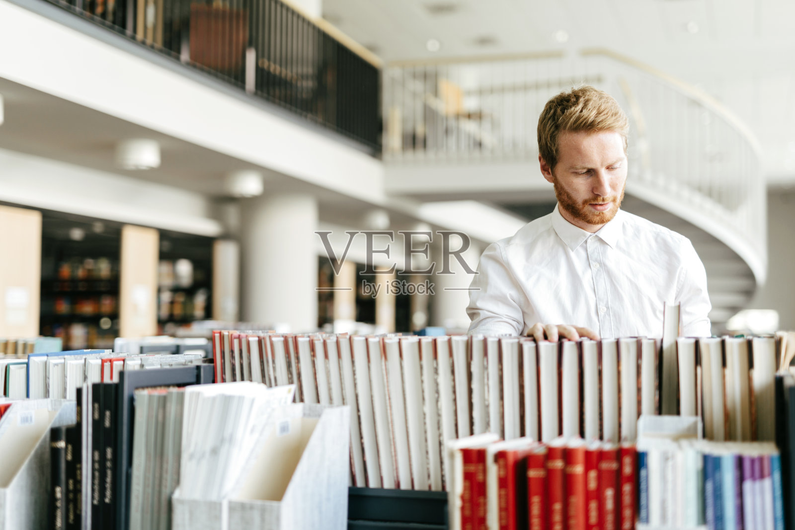 英俊的学生在漂亮的图书馆找书照片摄影图片