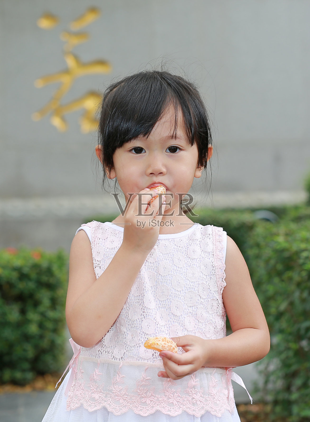 可爱的亚洲小女孩吃橘子水果在中国寺庙在泰国曼谷。照片摄影图片