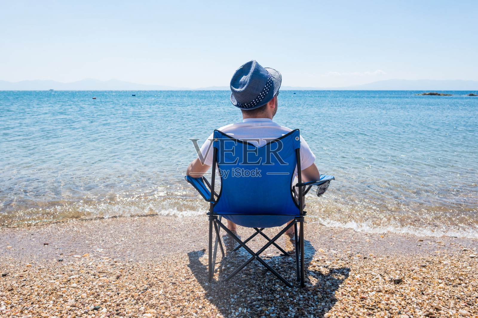 年轻的旅行者坐在海滩上欣赏风景照片摄影图片