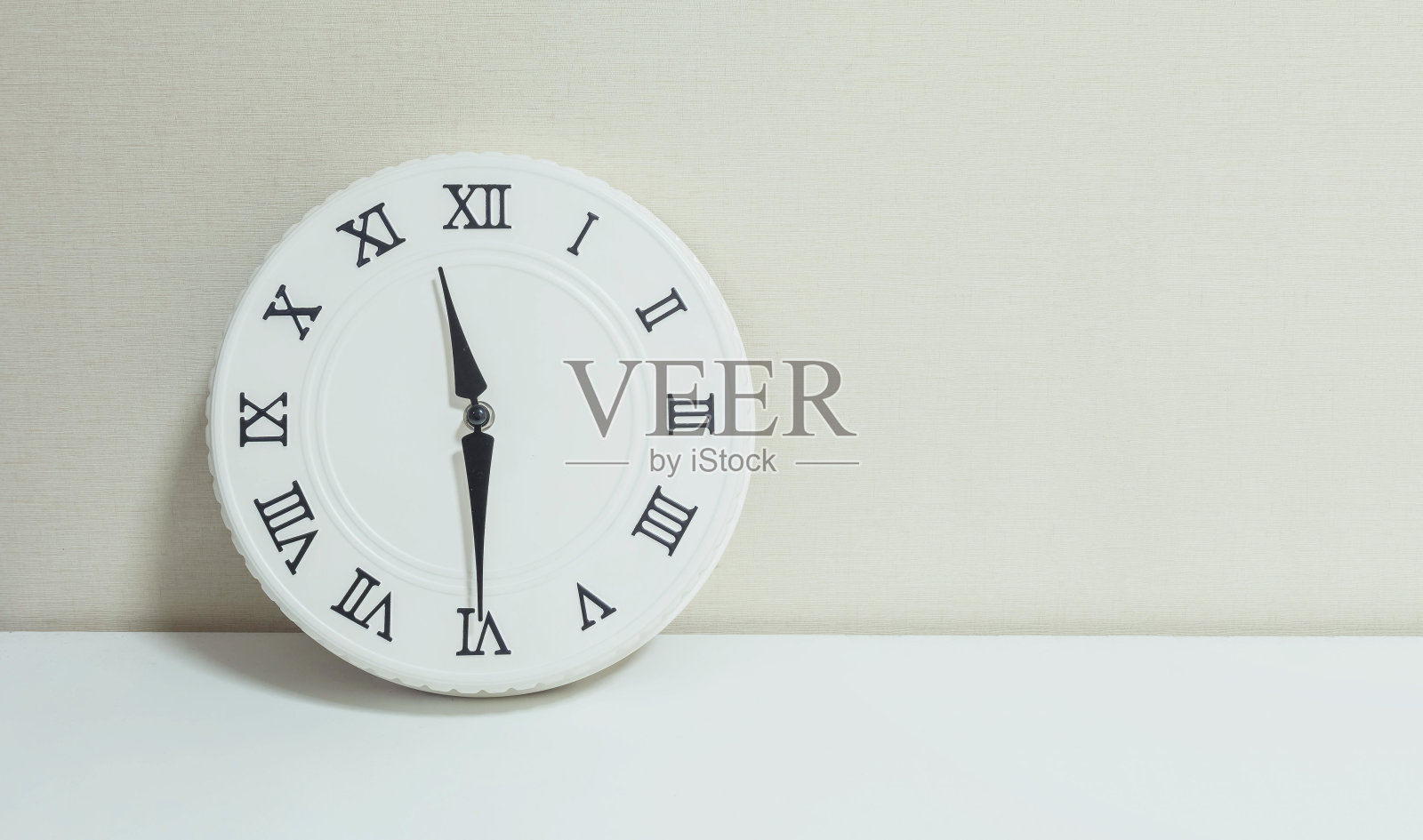 特写的白色时钟装饰显示11:30或11:30在白色的木头桌子和奶油色壁纸纹理背景与复制空间照片摄影图片