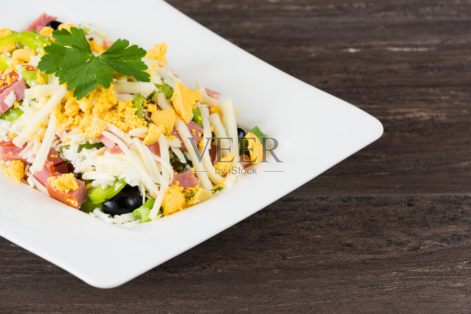 传统保加利亚牧羊人沙拉，用西红柿，辣椒，黄瓜，蘑菇，火腿，奶酪和鸡蛋放在白色的盘子里，放在灰色的木桌上。保加利亚美食，巴尔干文化照片摄影图片