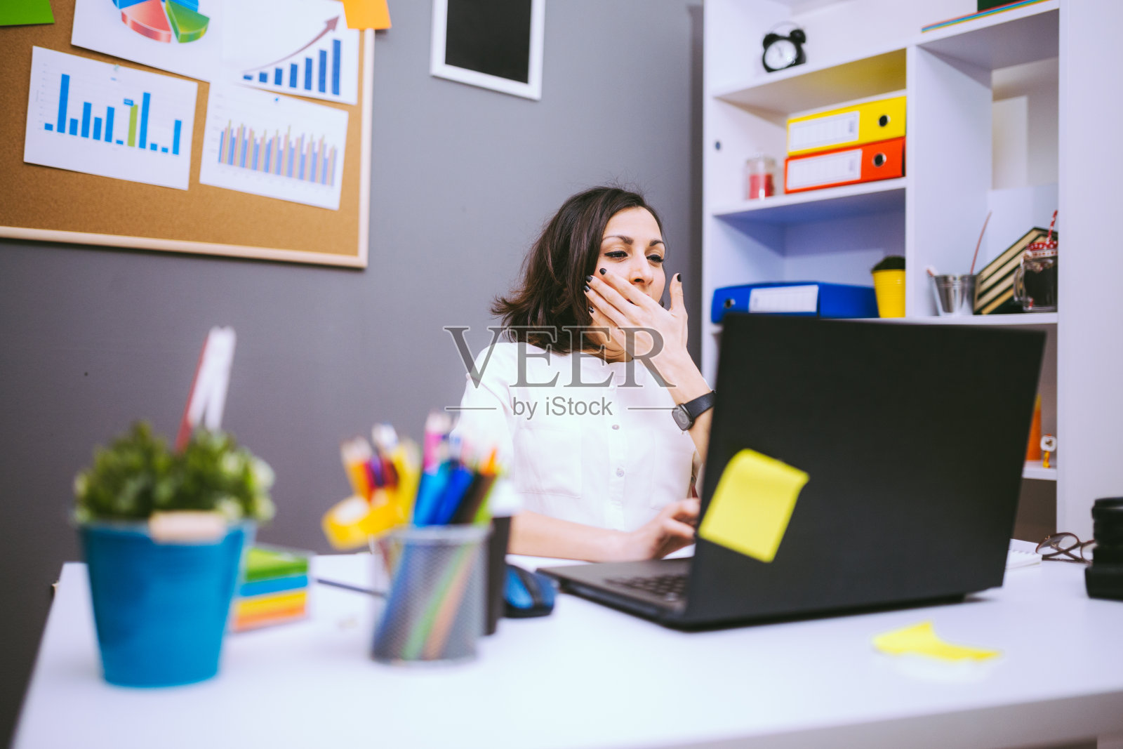 疲惫的女商人在工作场所打哈欠照片摄影图片