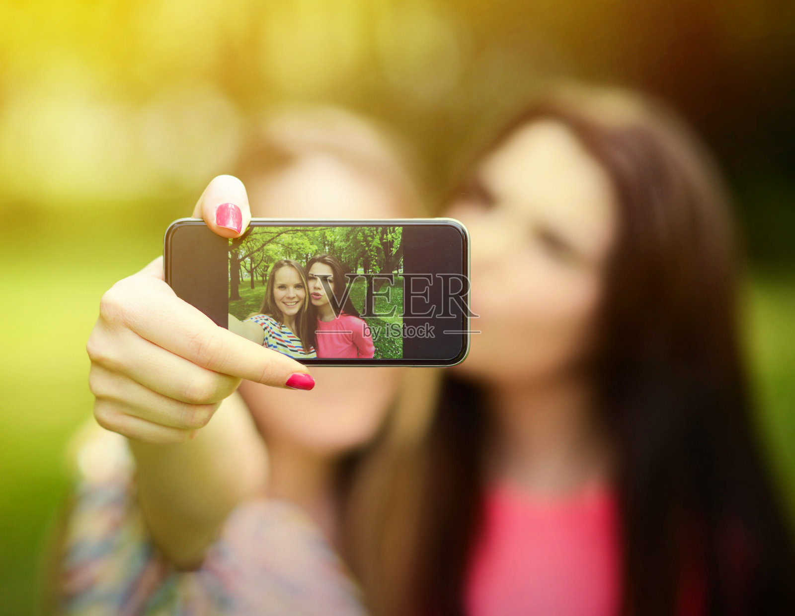 在美丽的夏日，朋友们在公园里用手机自拍照片摄影图片