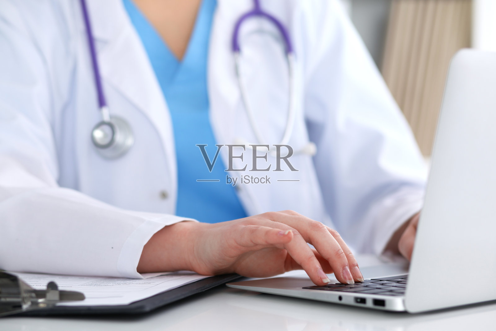 近距离的未知女医生打字笔记本电脑，而坐在桌子上照片摄影图片