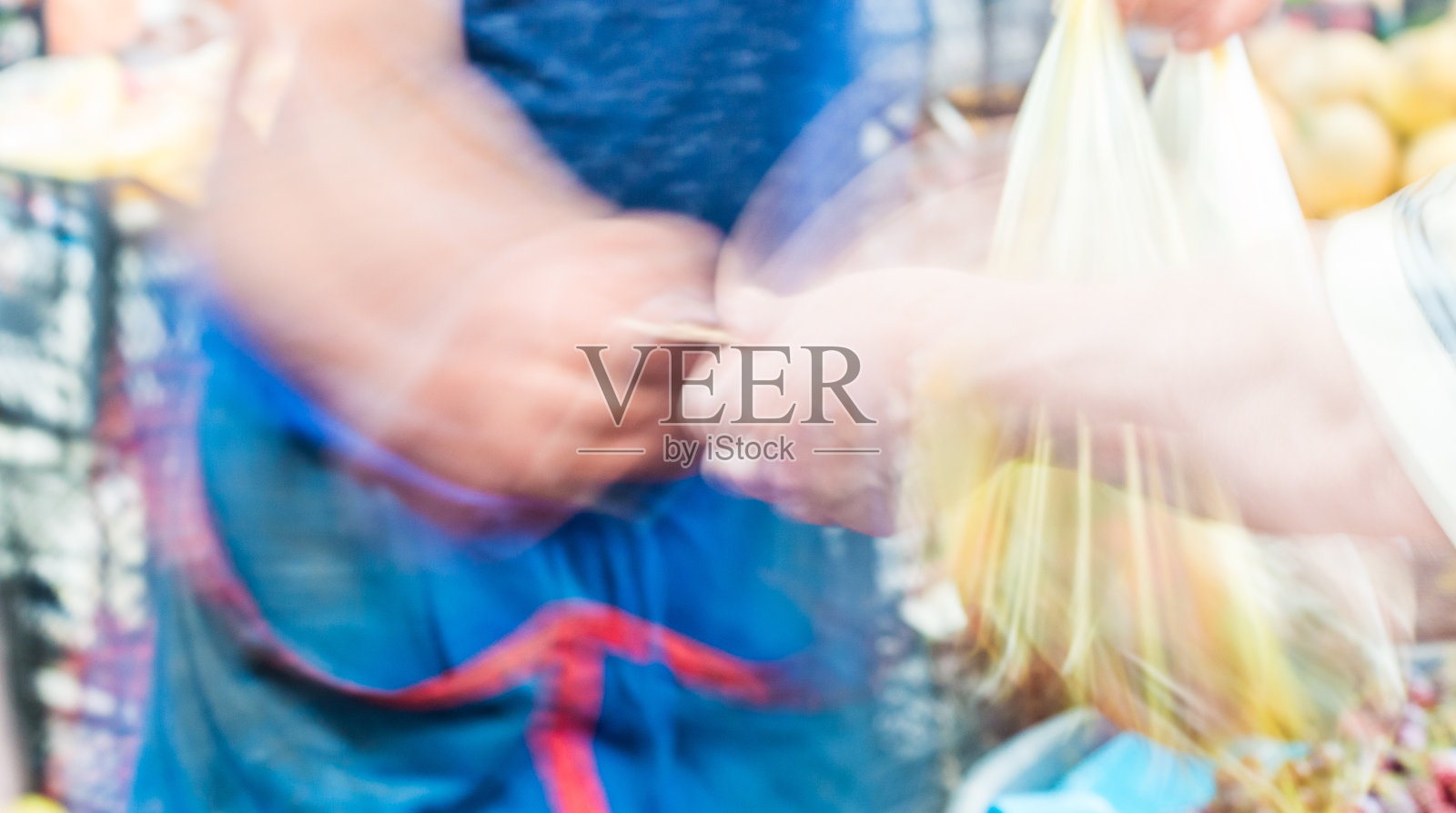 在当地的一个集市上，顾客把钱交给卖主的模糊抽象画面。照片摄影图片