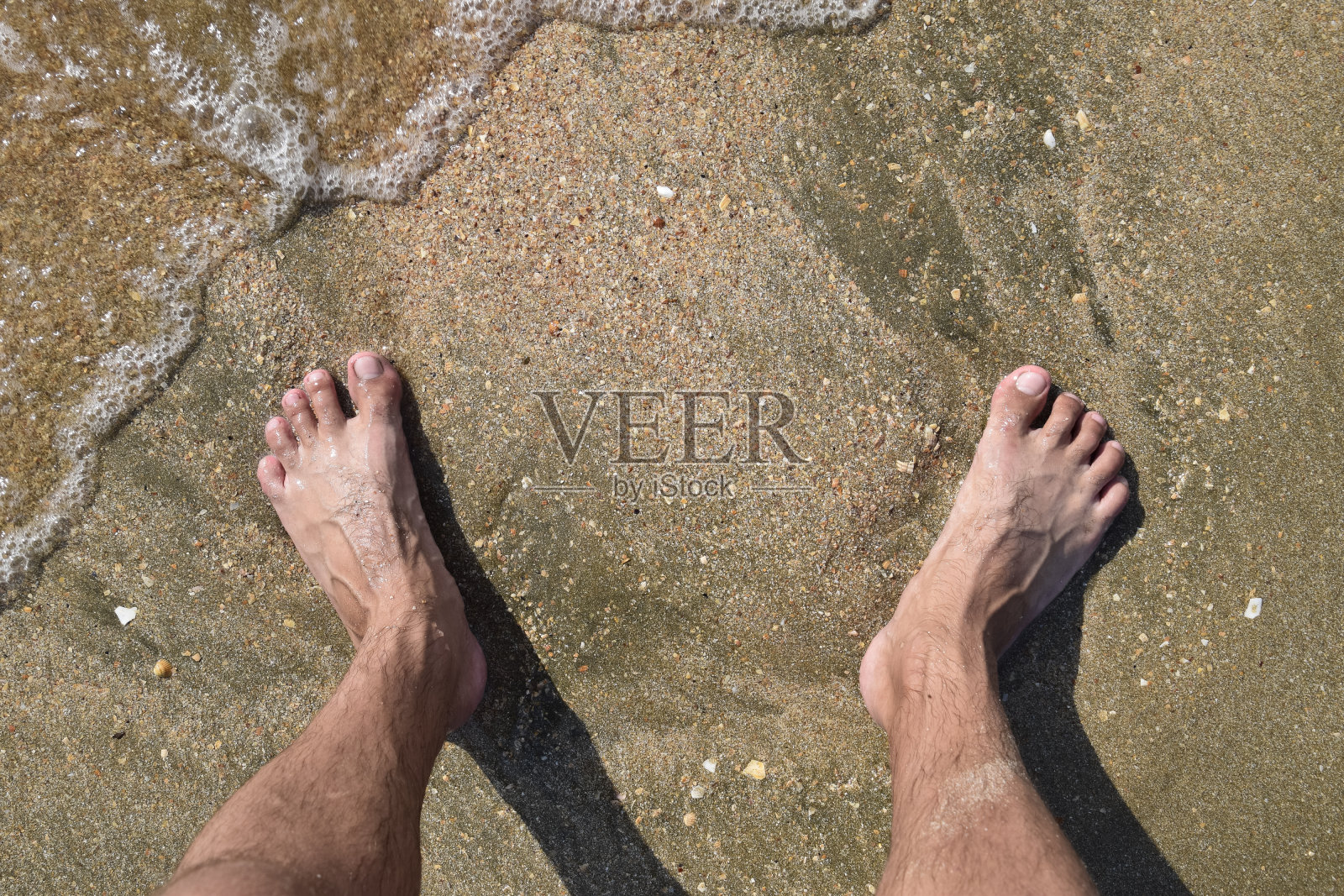 男人腿上的海沙靠近海浪照片摄影图片