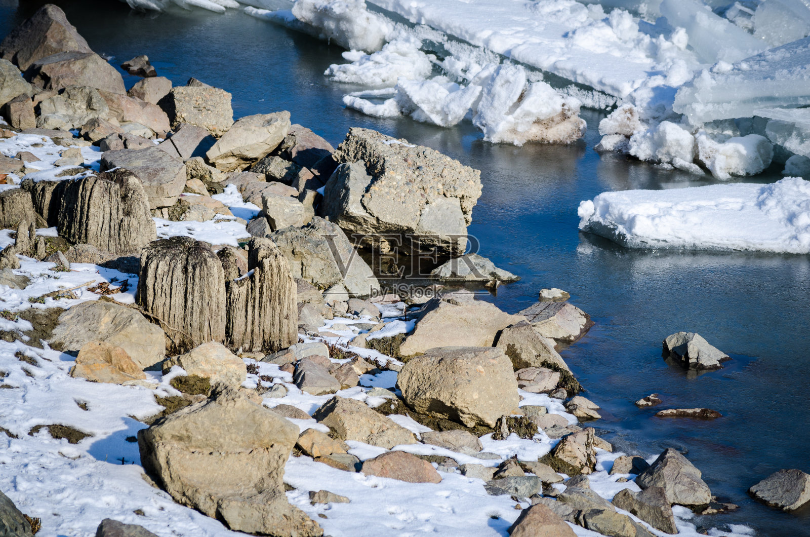 冰冻的多瑙河中的岩石。在冬天，水里的岩石被冰雪覆盖。塞尔维亚诺维萨德,。照片摄影图片