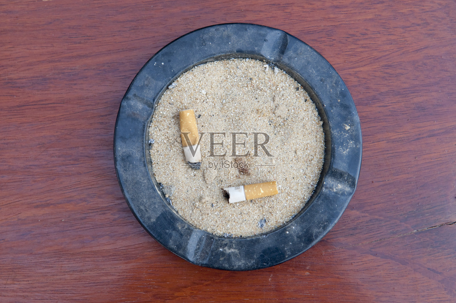 顶视图烟灰缸与使用过的香烟在木地板上照片摄影图片