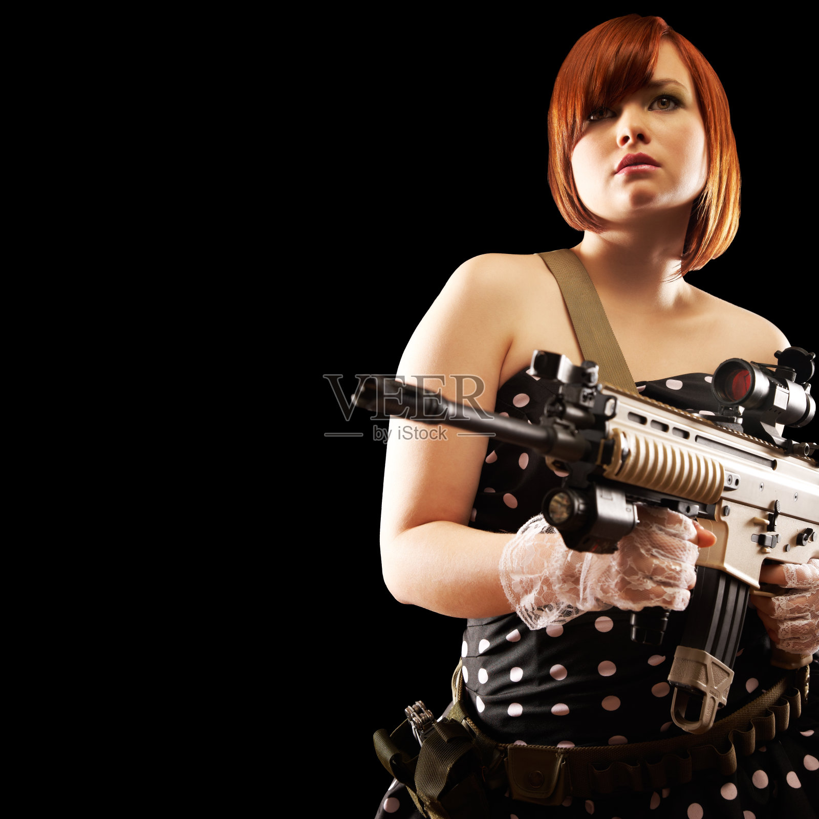 有魅力的年轻红发女人穿着裙子拿着步枪。黑色背景。照片摄影图片
