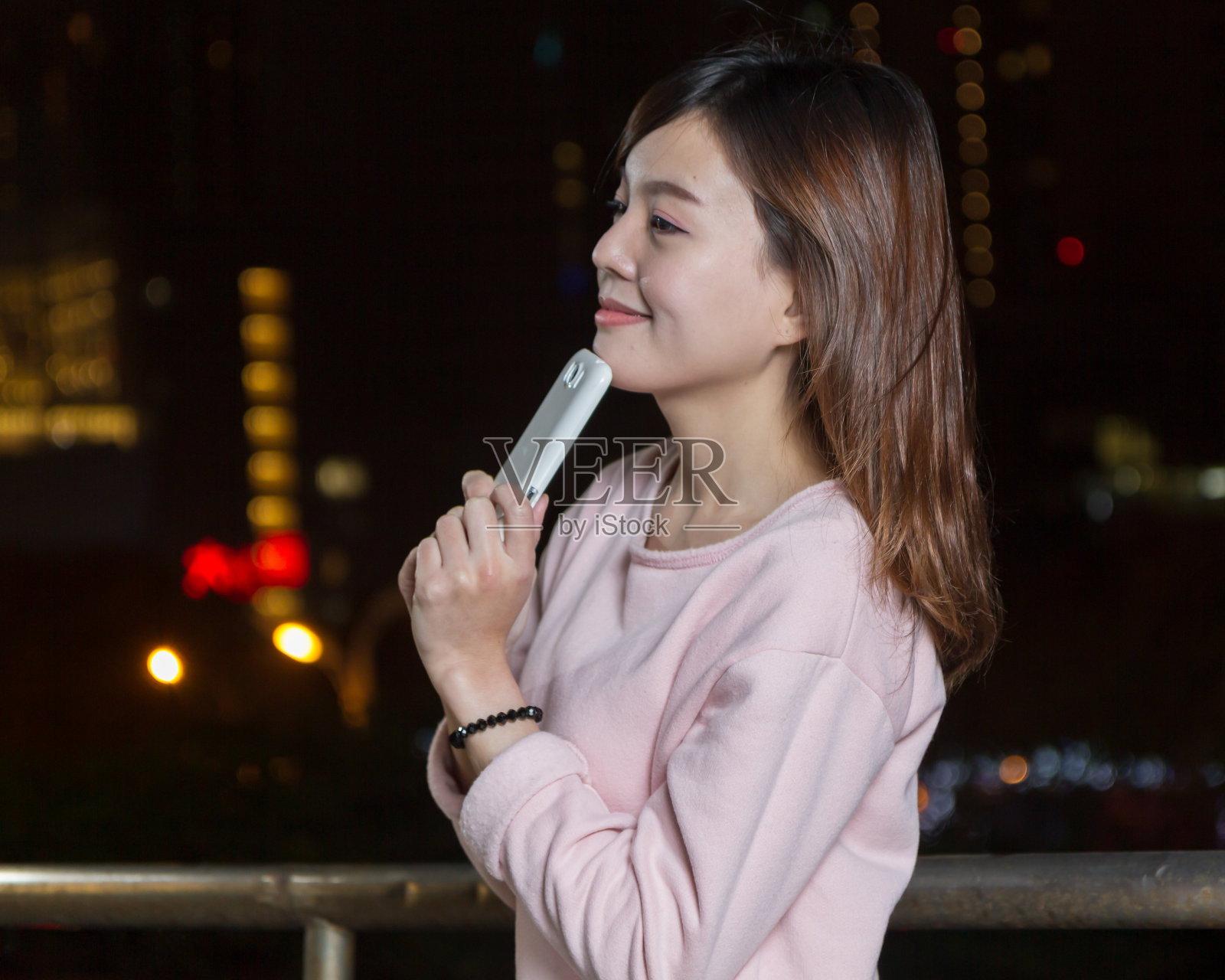 迷人的亚洲女人拿着手机在明亮的灯光下照片摄影图片