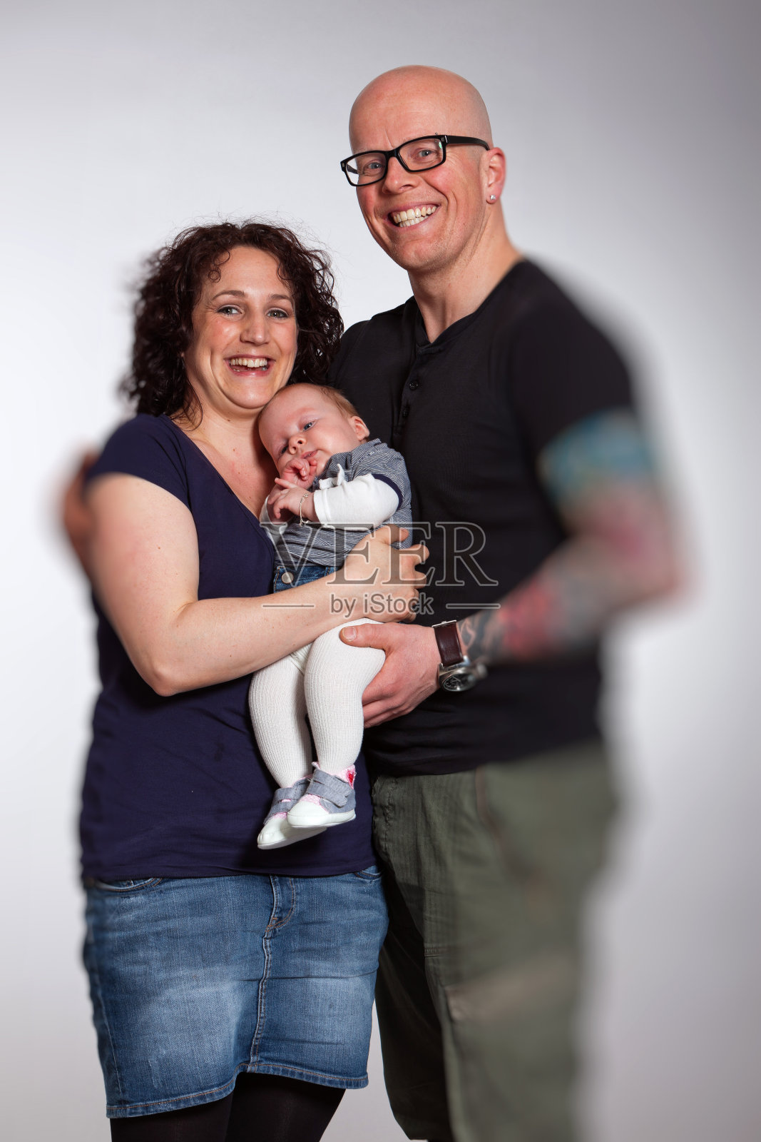 一对幸福的夫妇抱着他们的孩子。影棚拍摄。照片摄影图片