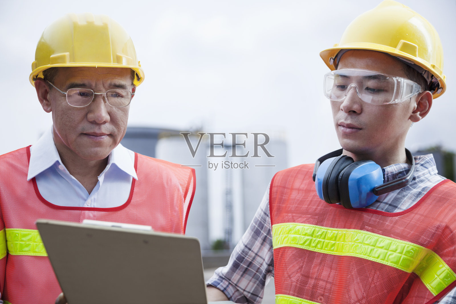 两名工程师低头看着工厂外的剪贴板照片摄影图片