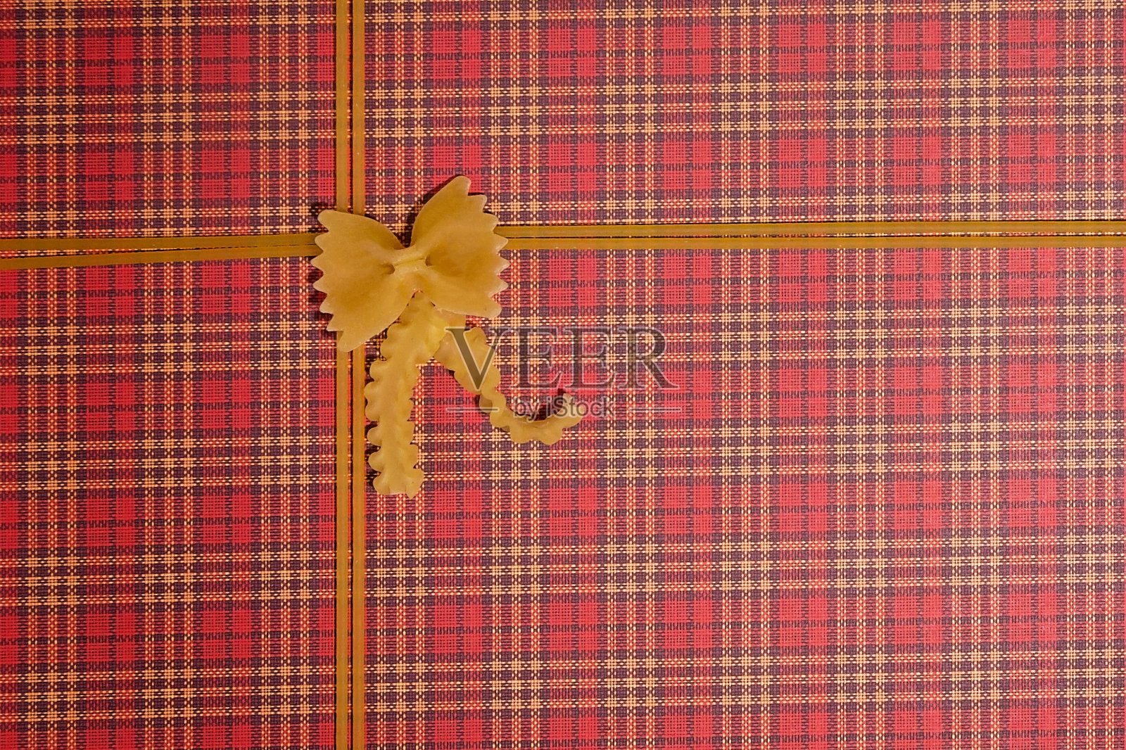 面框架。蝴蝶结形状的意大利面，红色的方格背景上有丝带。俯视图照片摄影图片