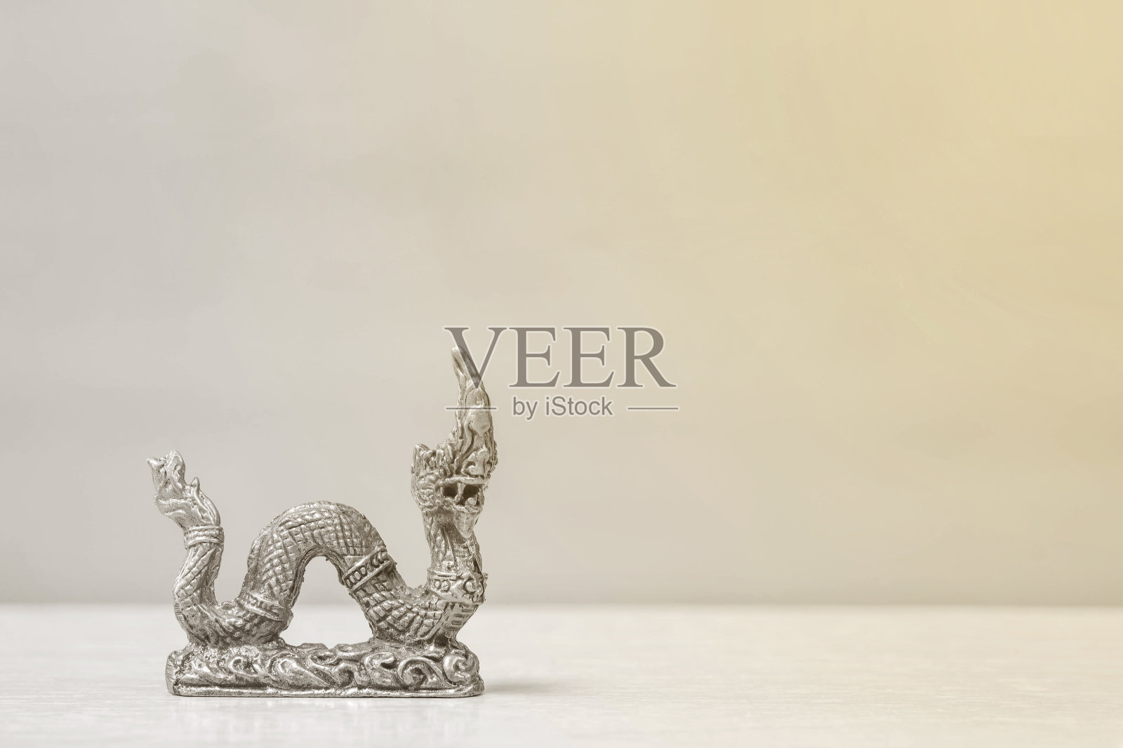 在房间纹理背景的模糊的木桌和木墙上，特写小铜王那伽雕像供人崇拜和装饰照片摄影图片