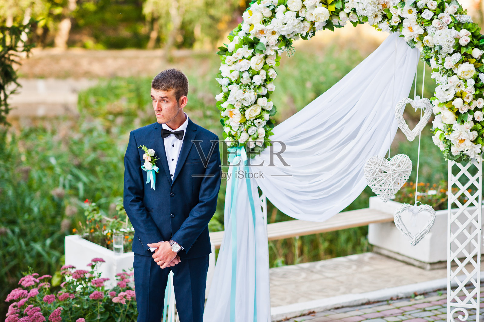 新郎独自待在婚礼拱门附近照片摄影图片
