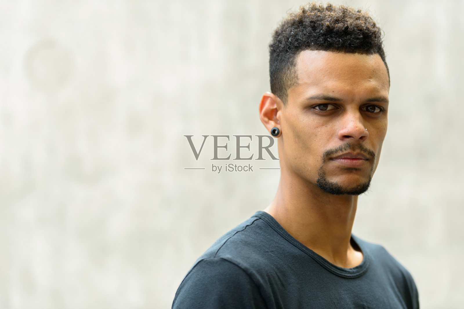 年轻英俊的非洲男子靠在水泥墙上的特写照片摄影图片