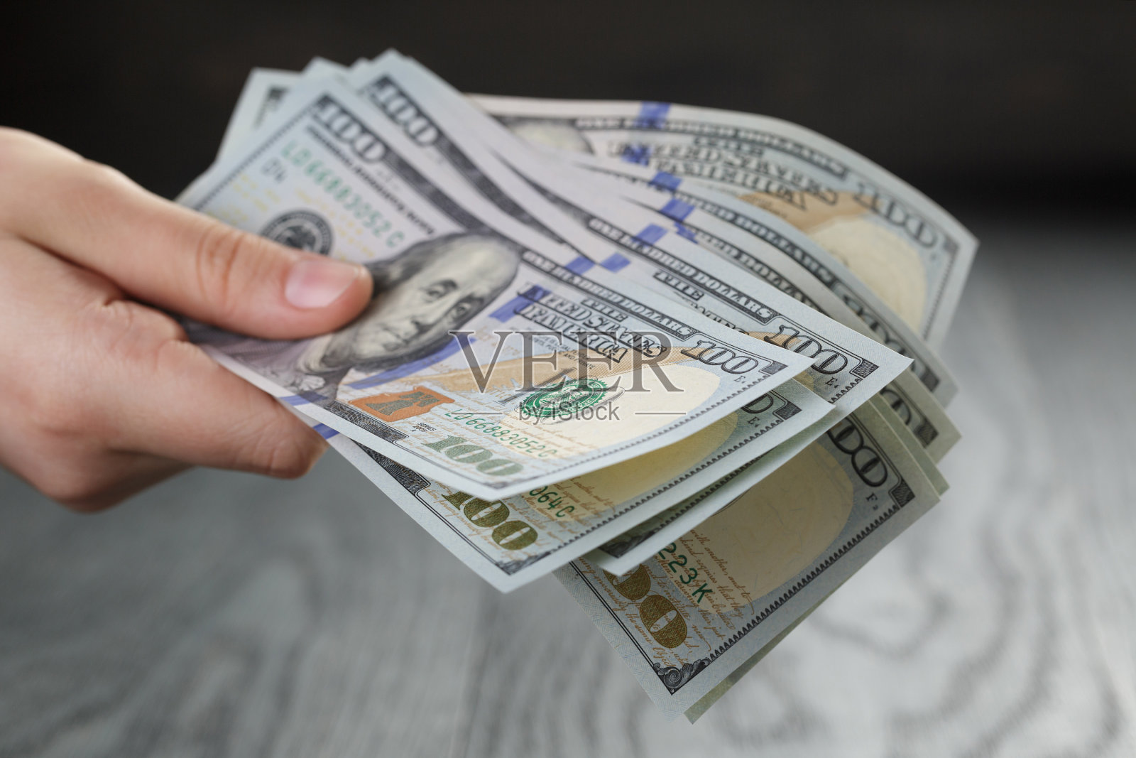 女性手握一堆美元，特写照片摄影图片