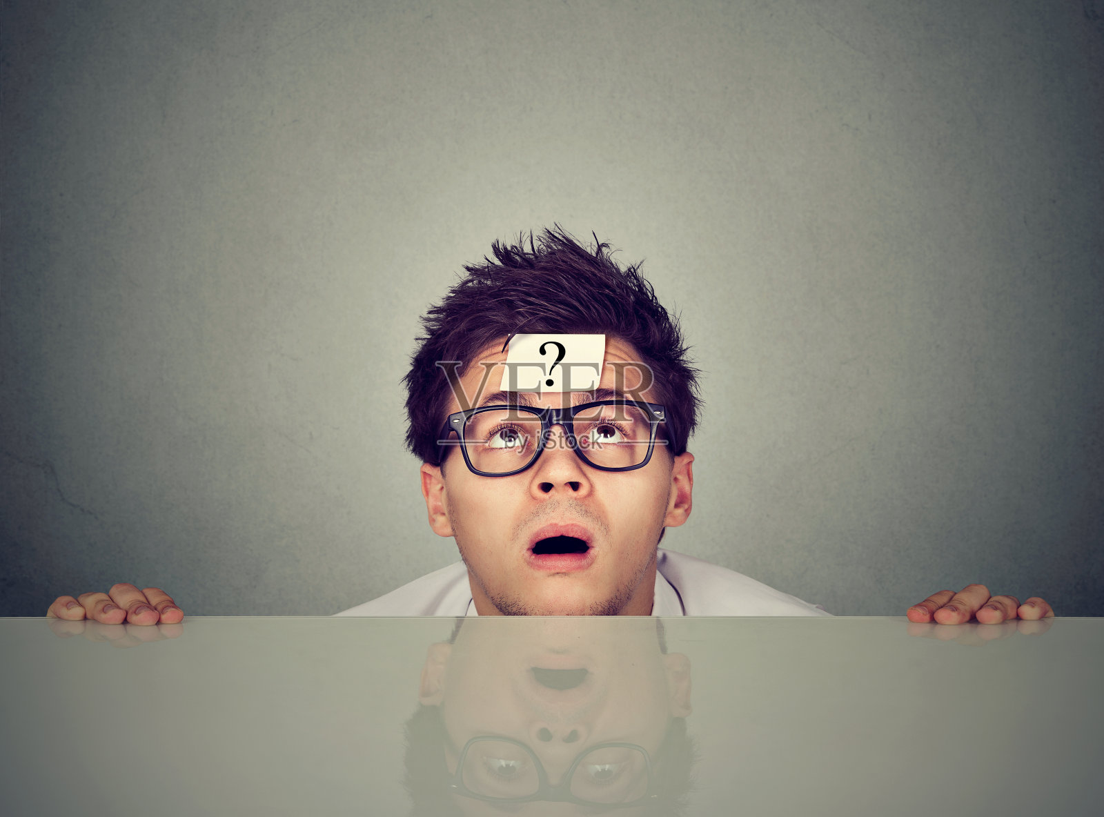 一个带着问号的思考的人从桌子底下抬头看照片摄影图片