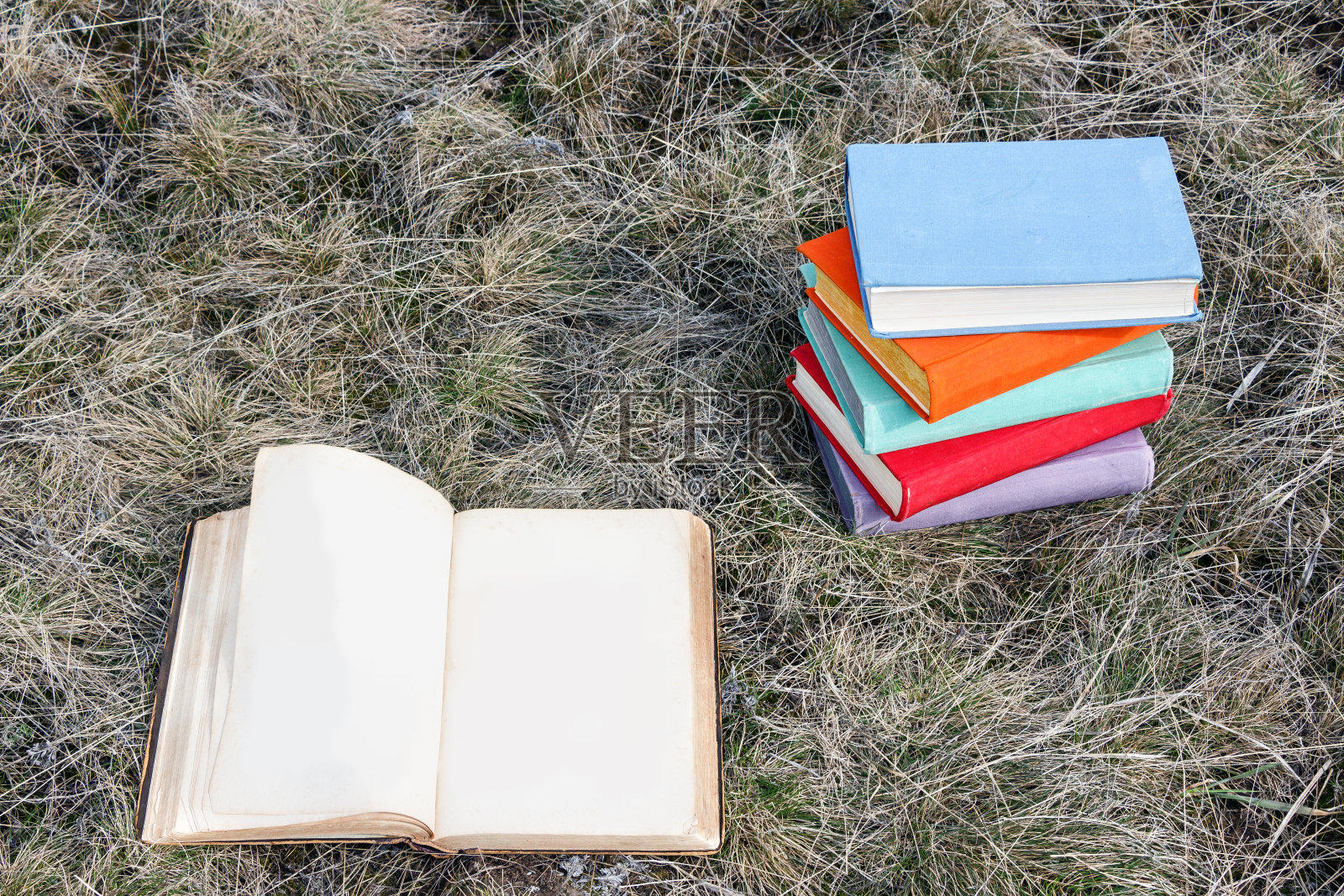 一堆彩色的书和打开的旧书在草地上。的成分。教育和学习的概念。照片摄影图片