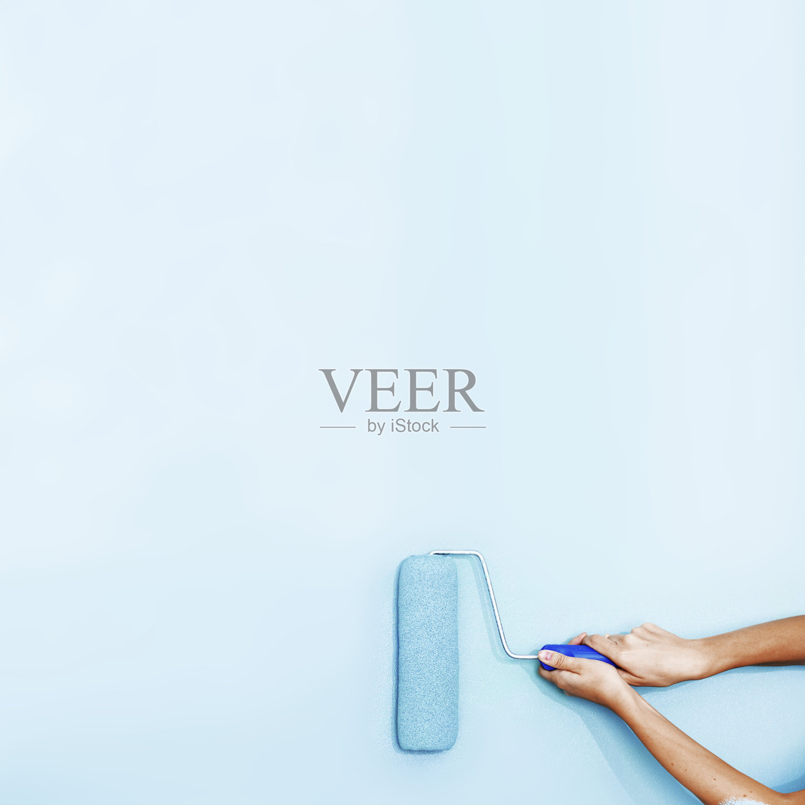 油漆工用滚筒刷把墙壁刷成淡蓝色照片摄影图片