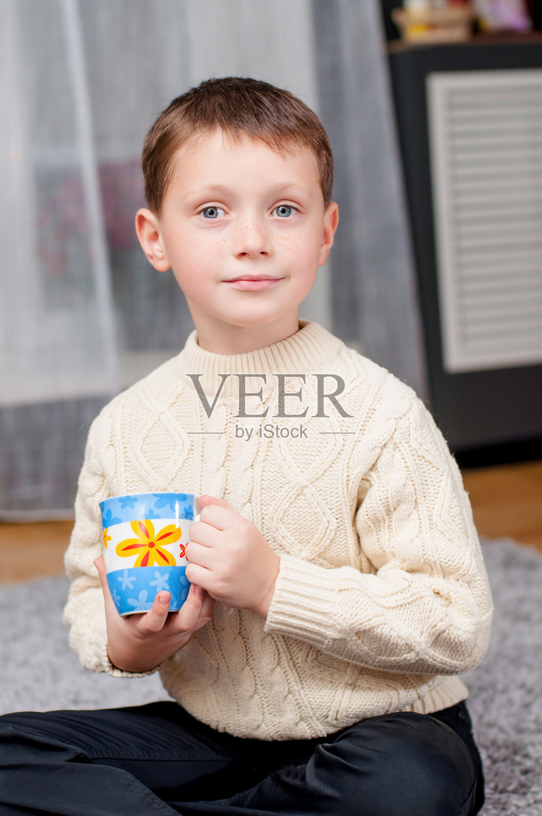 小男孩坐在家里的地毯上照片摄影图片