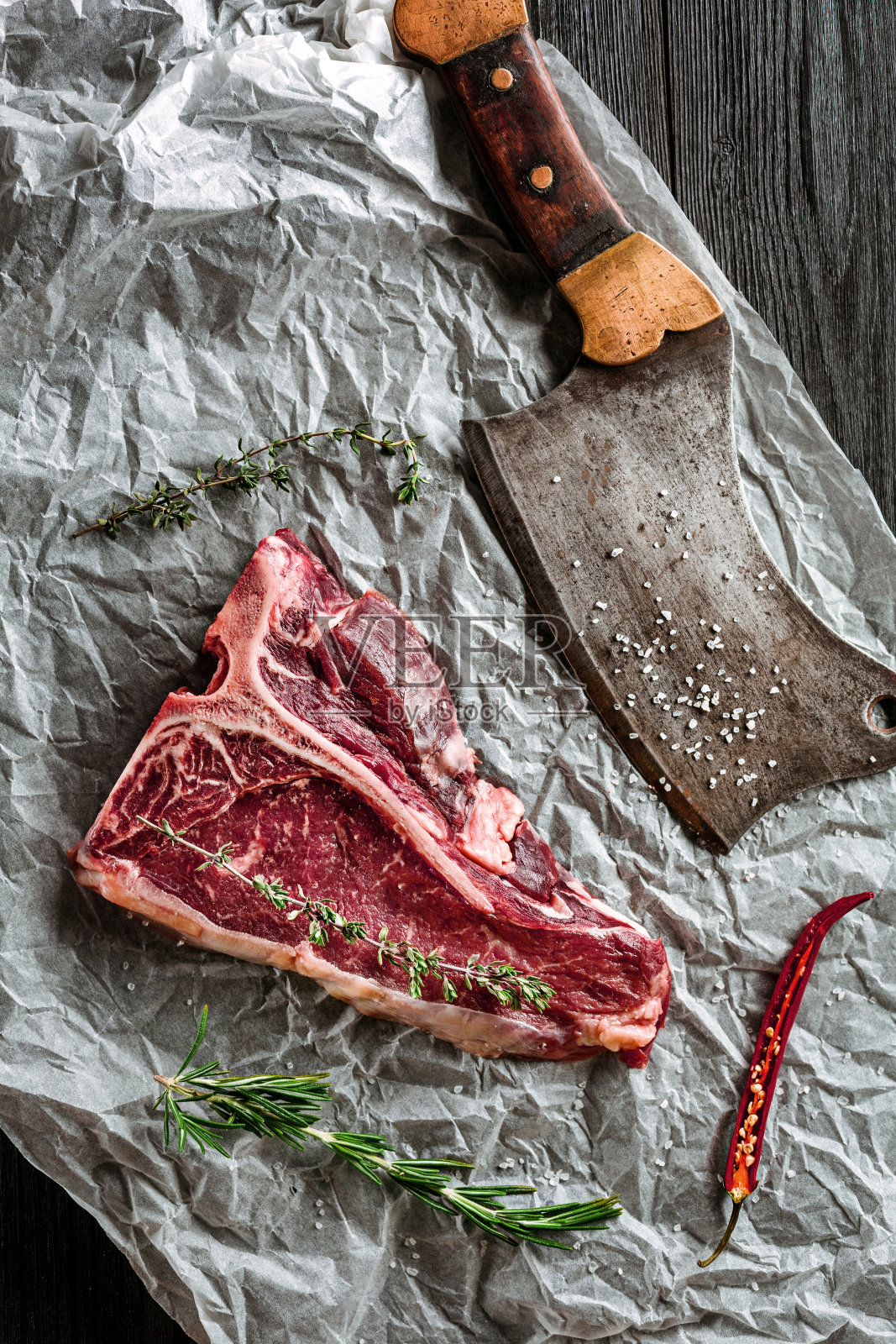 生的、干燥的、陈年的t骨牛排，配上新鲜的香草和切肉刀烧烤照片摄影图片