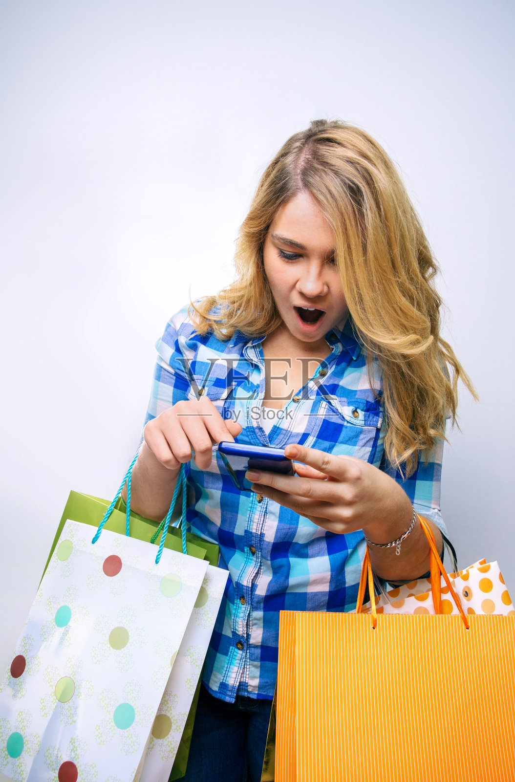 拿着购物袋看手机的少女照片摄影图片