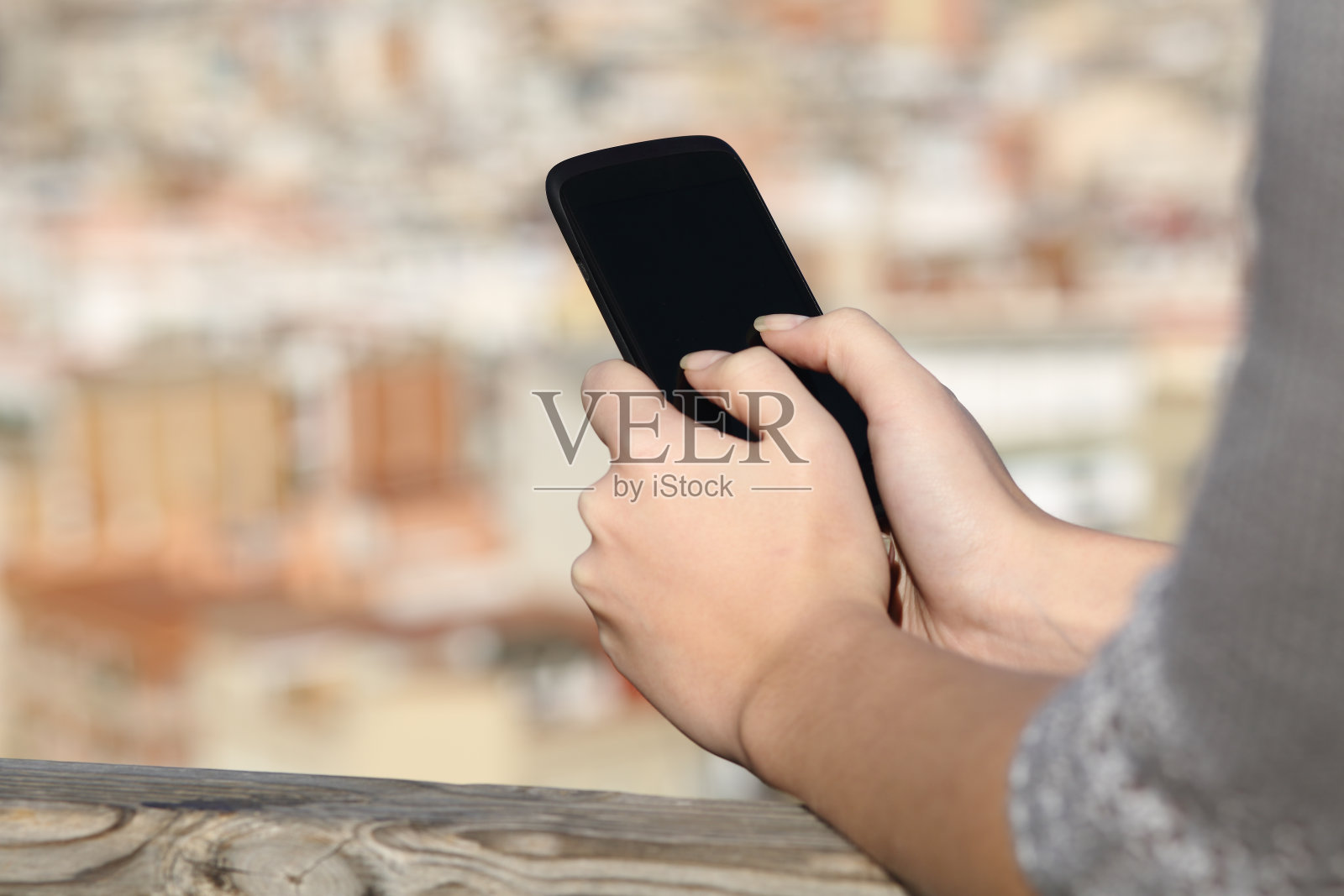 女人用都市背景的智能手机发短信照片摄影图片