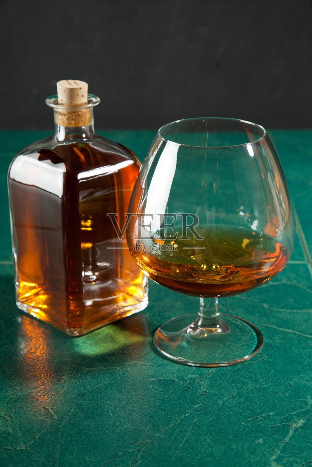 绿色桌上放着一杯白兰地和一瓶照片摄影图片