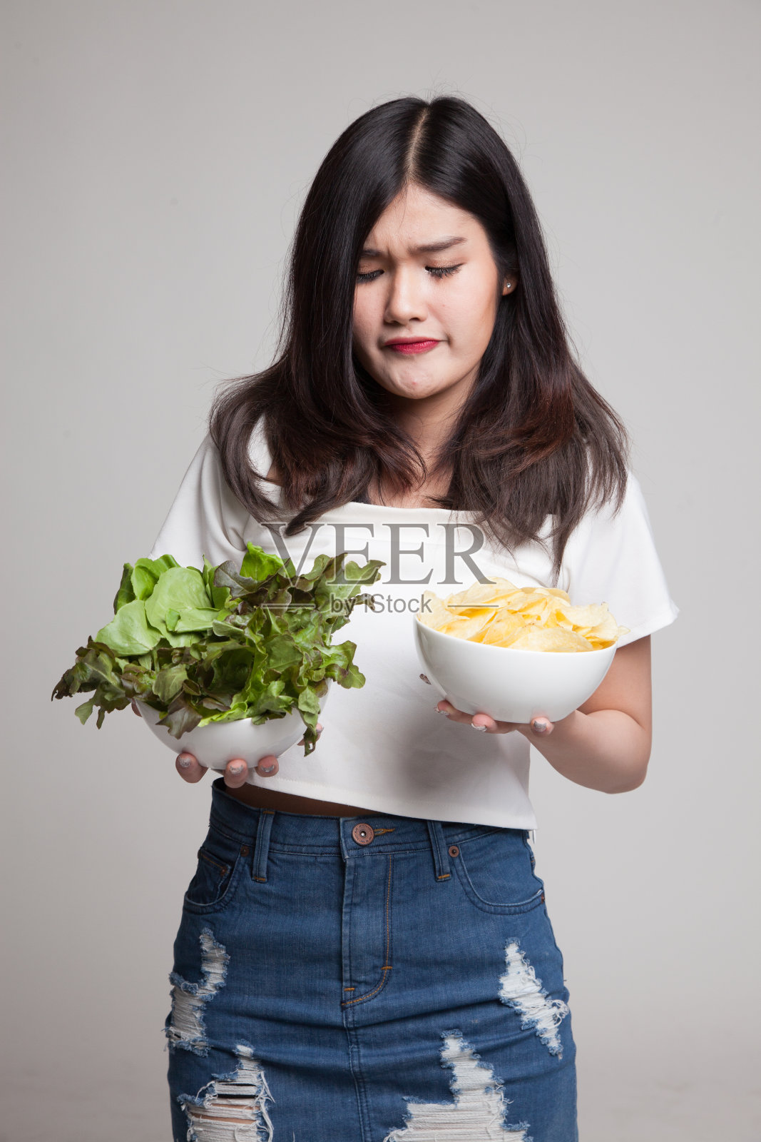 年轻的亚洲女人，配着薯片和沙拉。照片摄影图片