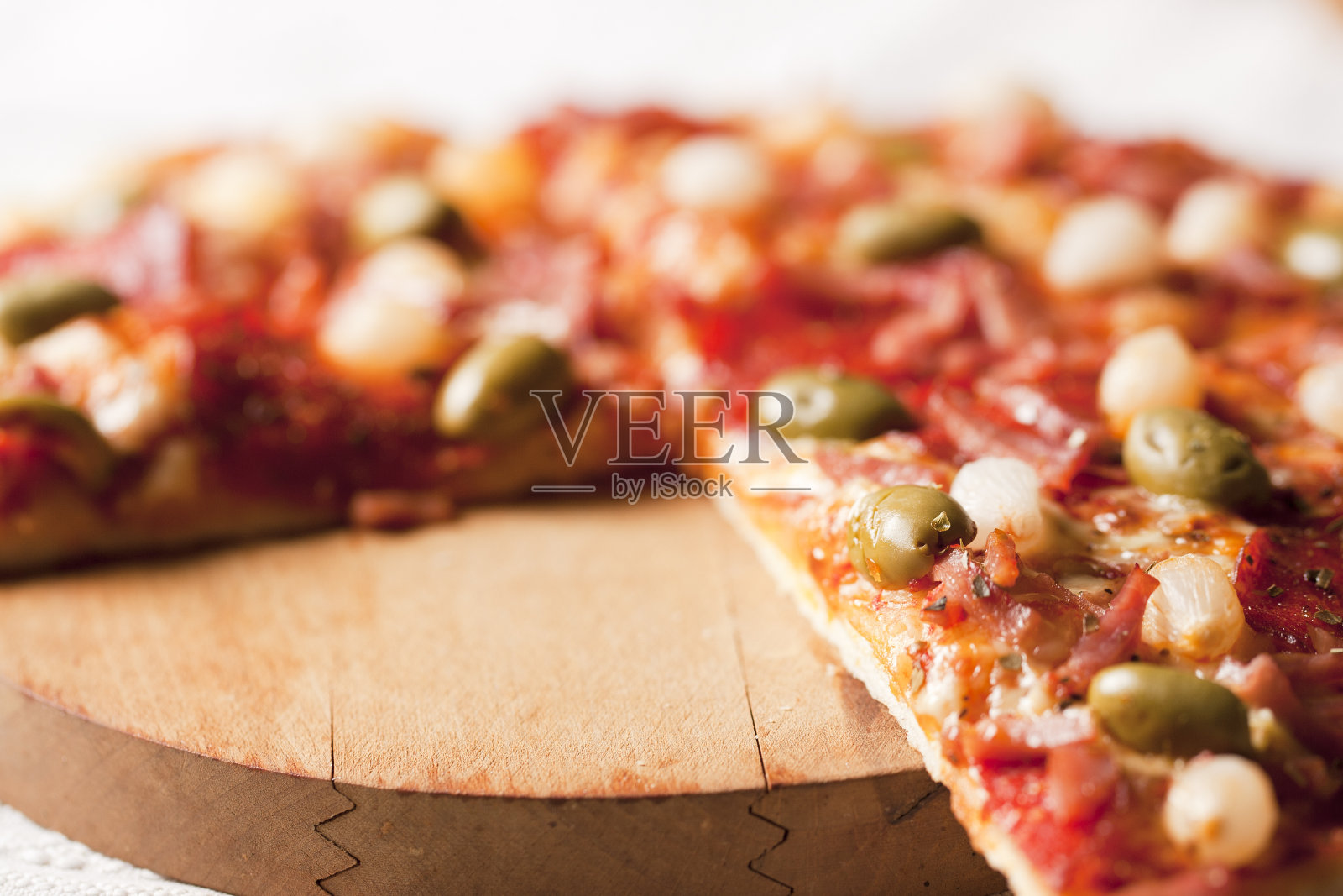 有火腿，意大利腊肠，橄榄，培根，洋葱的比萨照片摄影图片