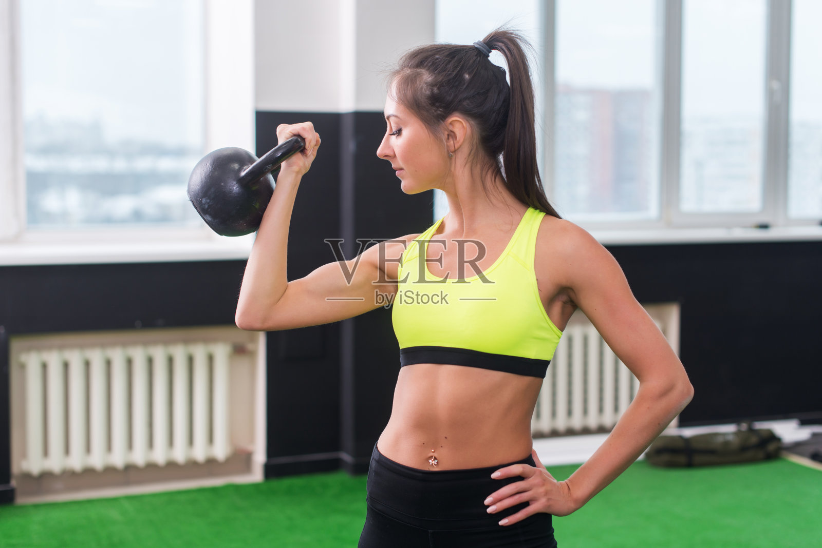 年轻的健康女子做运动举壶铃，锻炼肱二头肌照片摄影图片