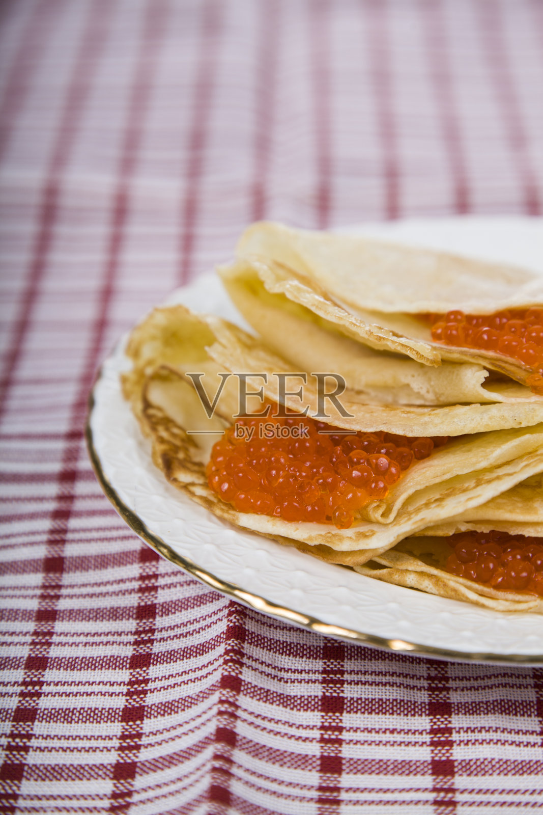 桌子上有煎饼和红鱼子酱。照片摄影图片