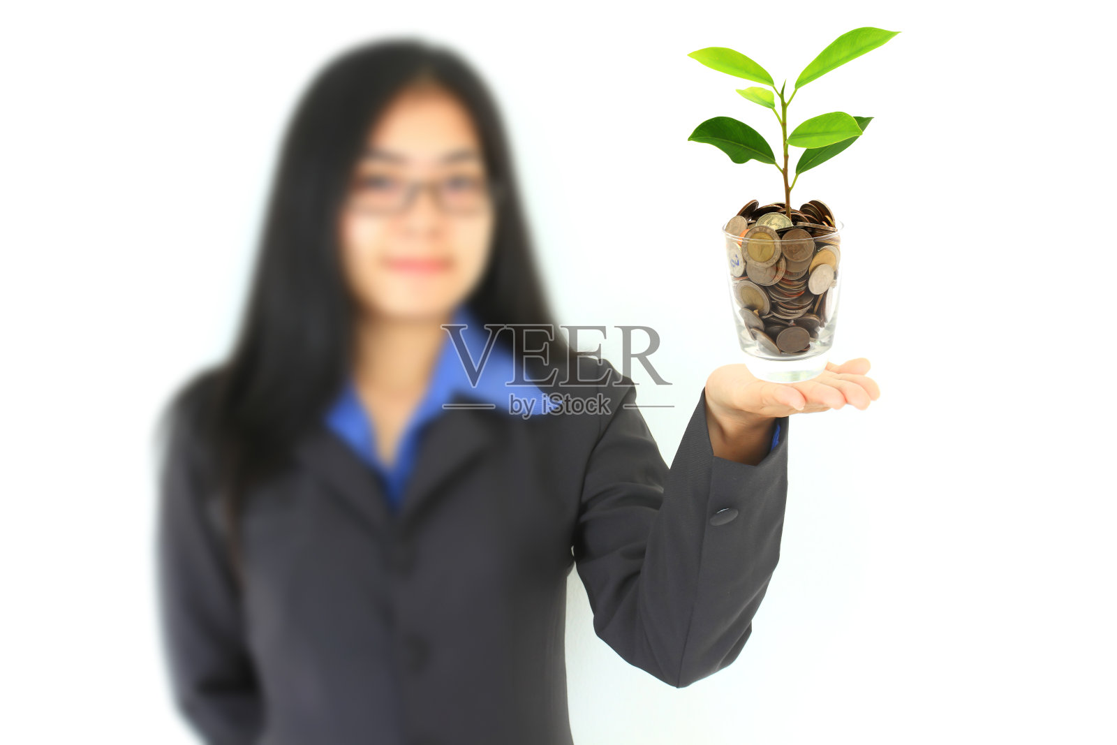 漂亮的年轻女商人拿着一株正在生长的植物和硬币(S照片摄影图片