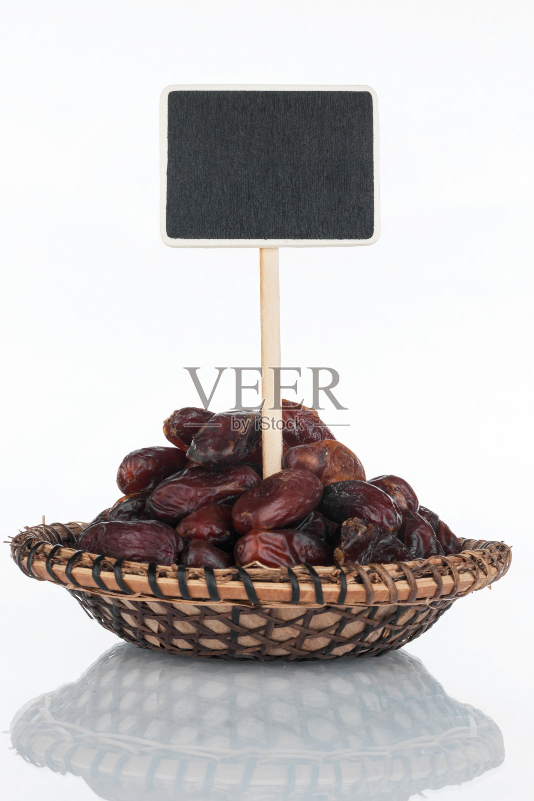 有一堆干枣的盘子，还有它的倒影，价格标签，指针。照片摄影图片