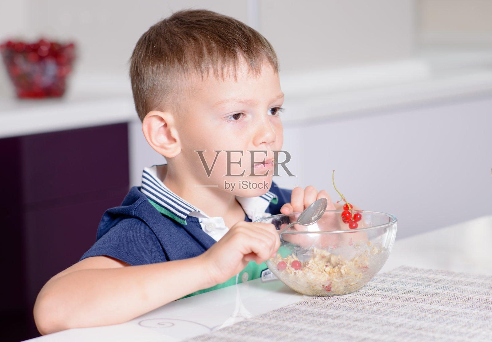 小男孩在早餐桌上吃着一碗麦片照片摄影图片