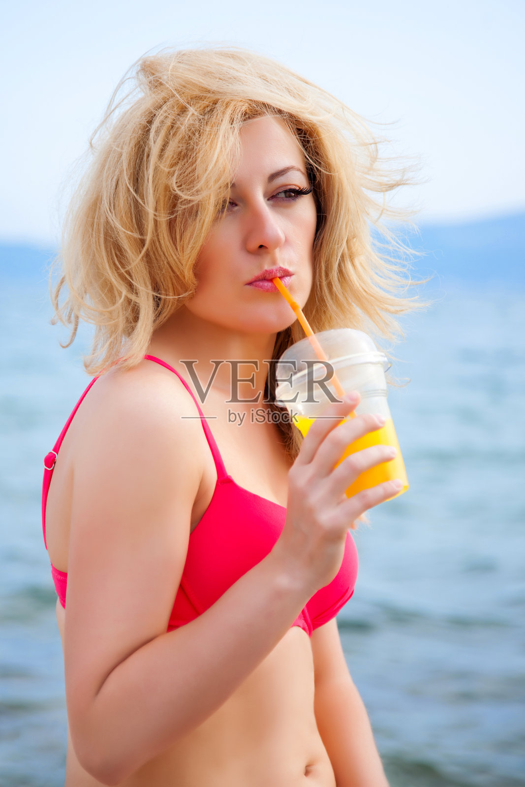 站在海滩上喝果汁的女人照片摄影图片