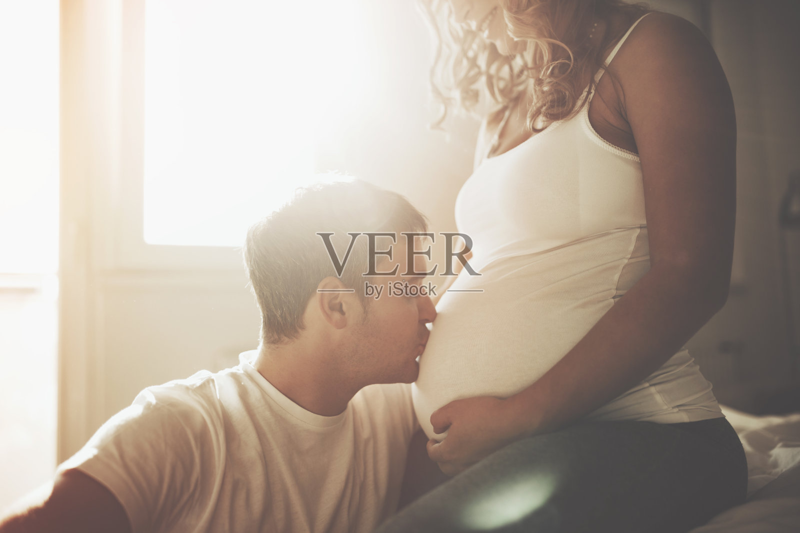 丈夫温柔地亲吻怀孕妻子的肚子照片摄影图片