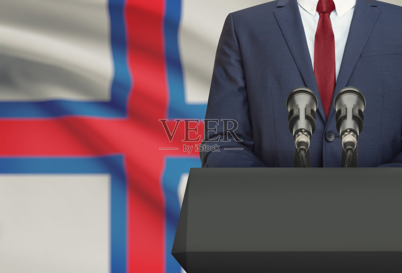 商人或政治家在讲坛后发表演讲，背景是国旗-法罗群岛照片摄影图片