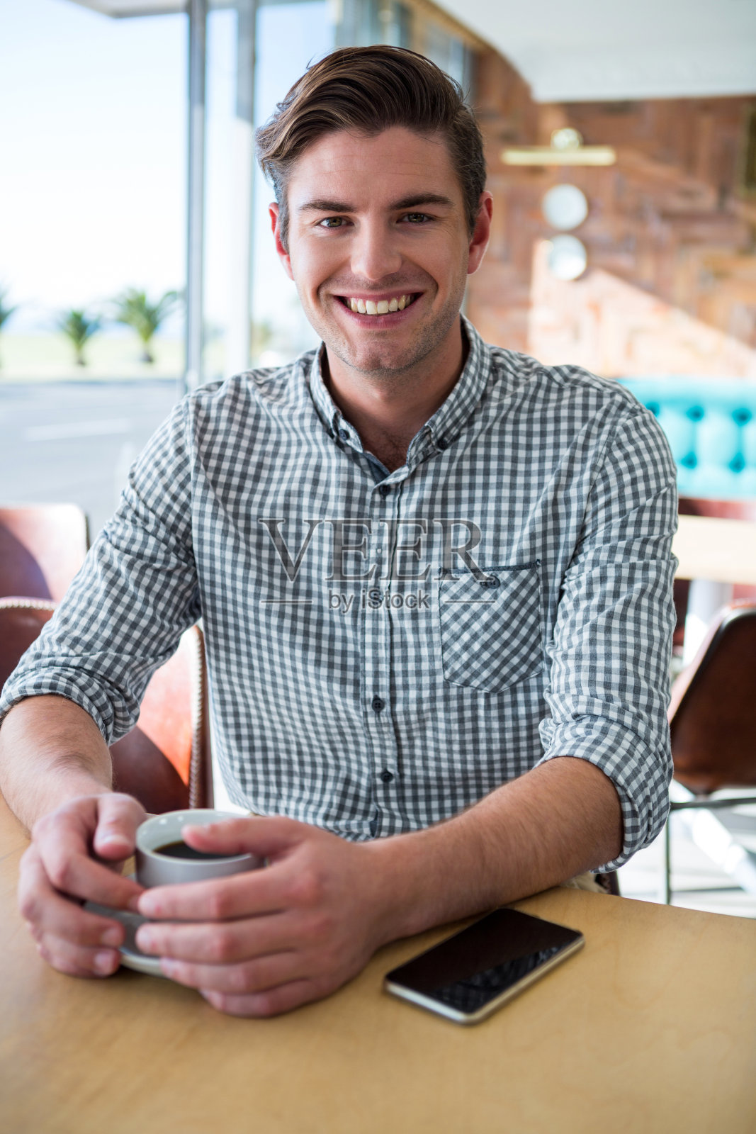 一个微笑的男人坐在咖啡店里的肖像照片摄影图片