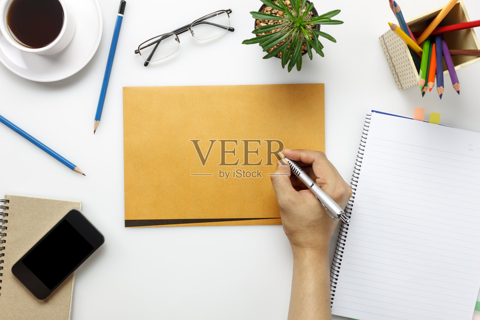 俯视图配件商务办公桌与商人。商人与文件工作，手机，咖啡，笔记本，仙人掌，剪贴板在白色的办公桌与复印空间。照片摄影图片