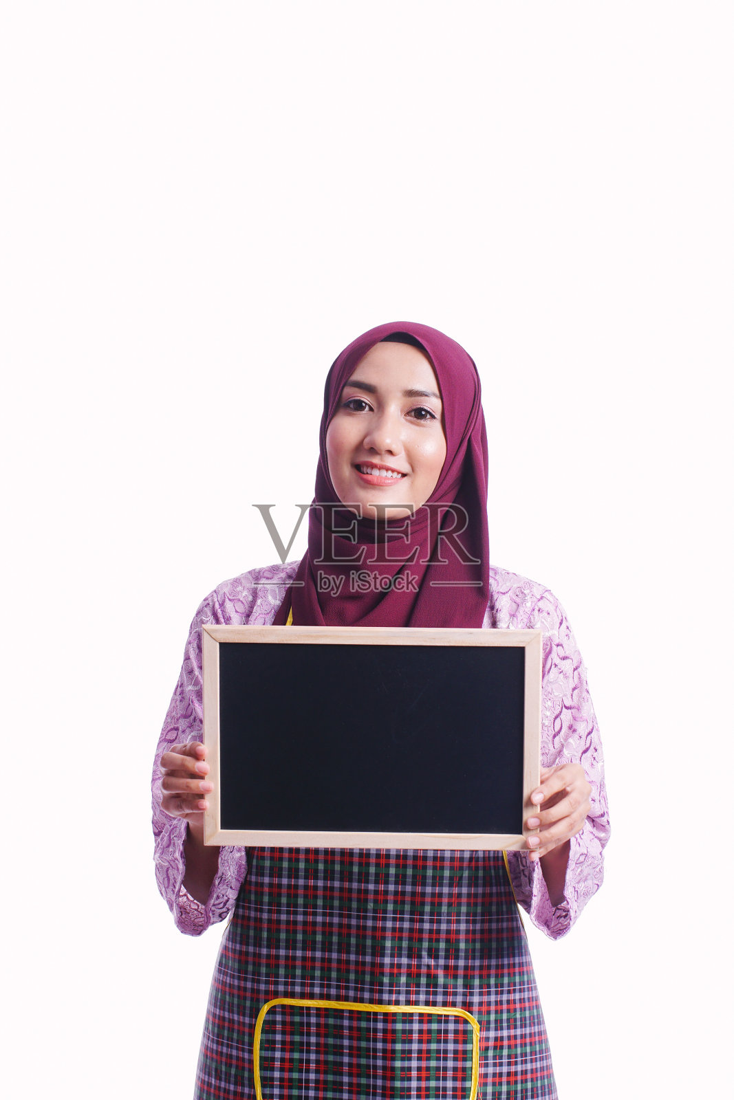 美丽的女人穿着围裙站在一块空白的黑板上，不同的肢体语言和表情孤立在白色的背景上——厨房，清洁，女佣和服务理念照片摄影图片