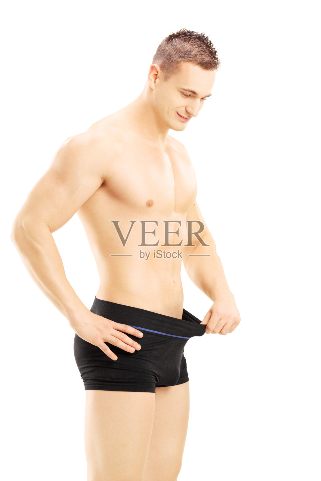 年轻的赤膊男子在看他的裤子照片摄影图片