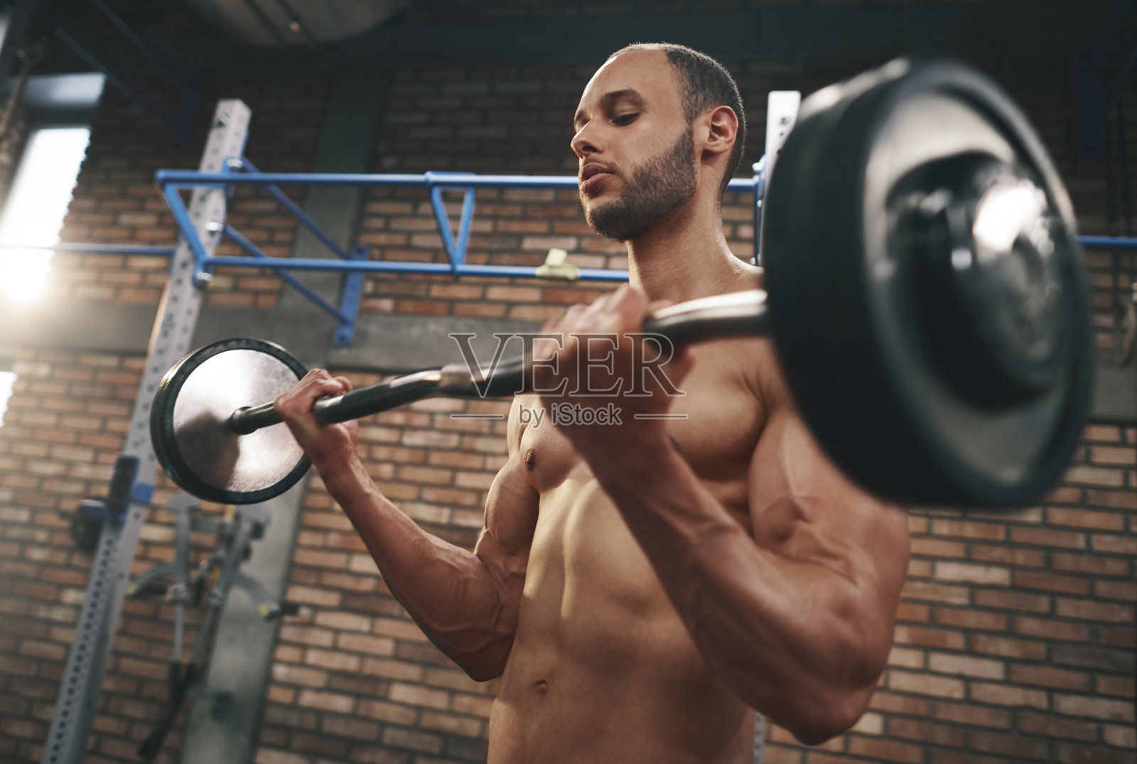 在体育馆举杠铃的肌肉男照片摄影图片
