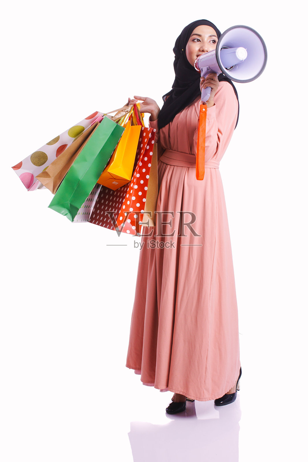 女人穿着一件连衣裙拿着购物袋，享受在白色的背景上购物，消费和生活方式的概念照片摄影图片