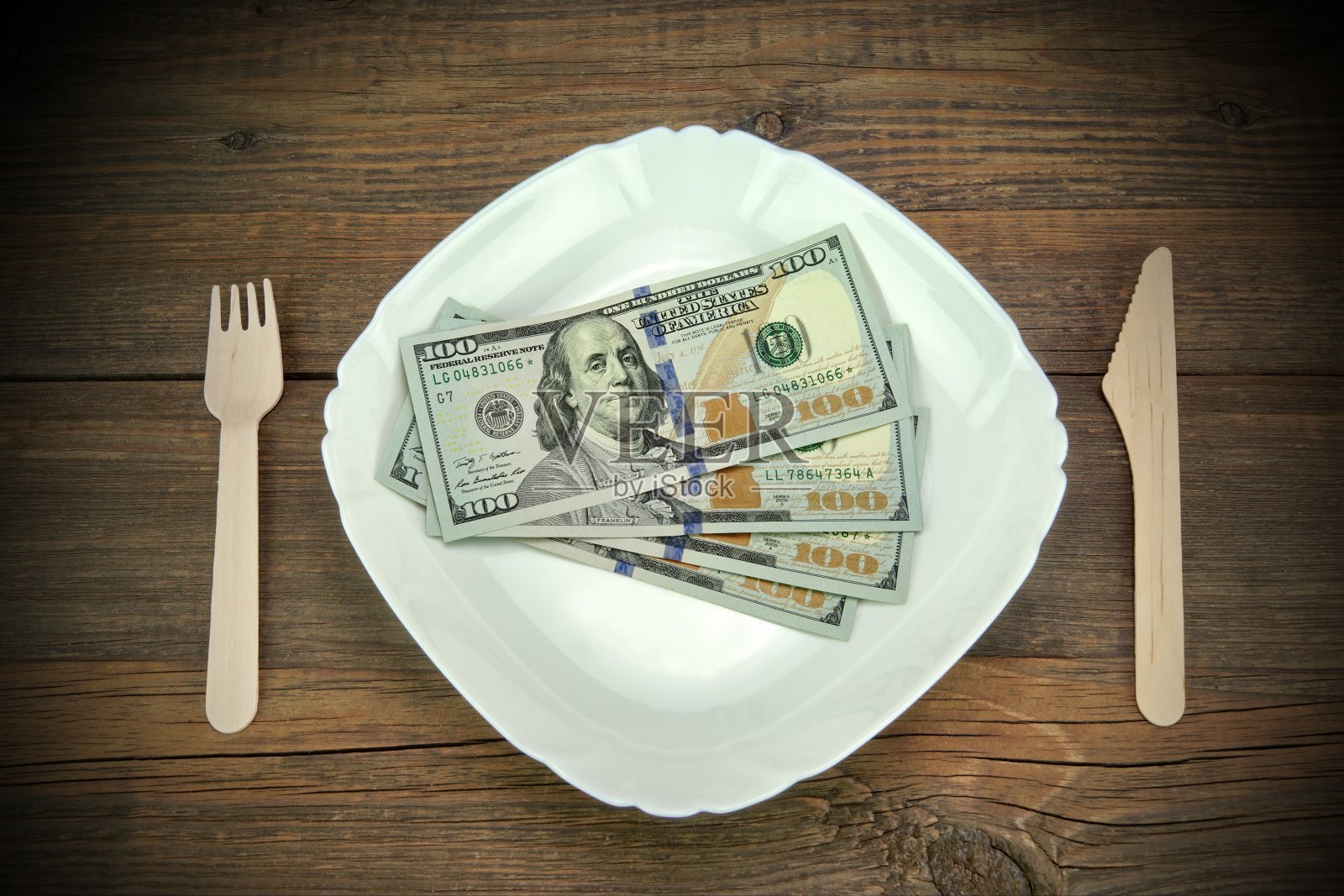 盘子上的一百美元钞票。木头的背景。照片摄影图片