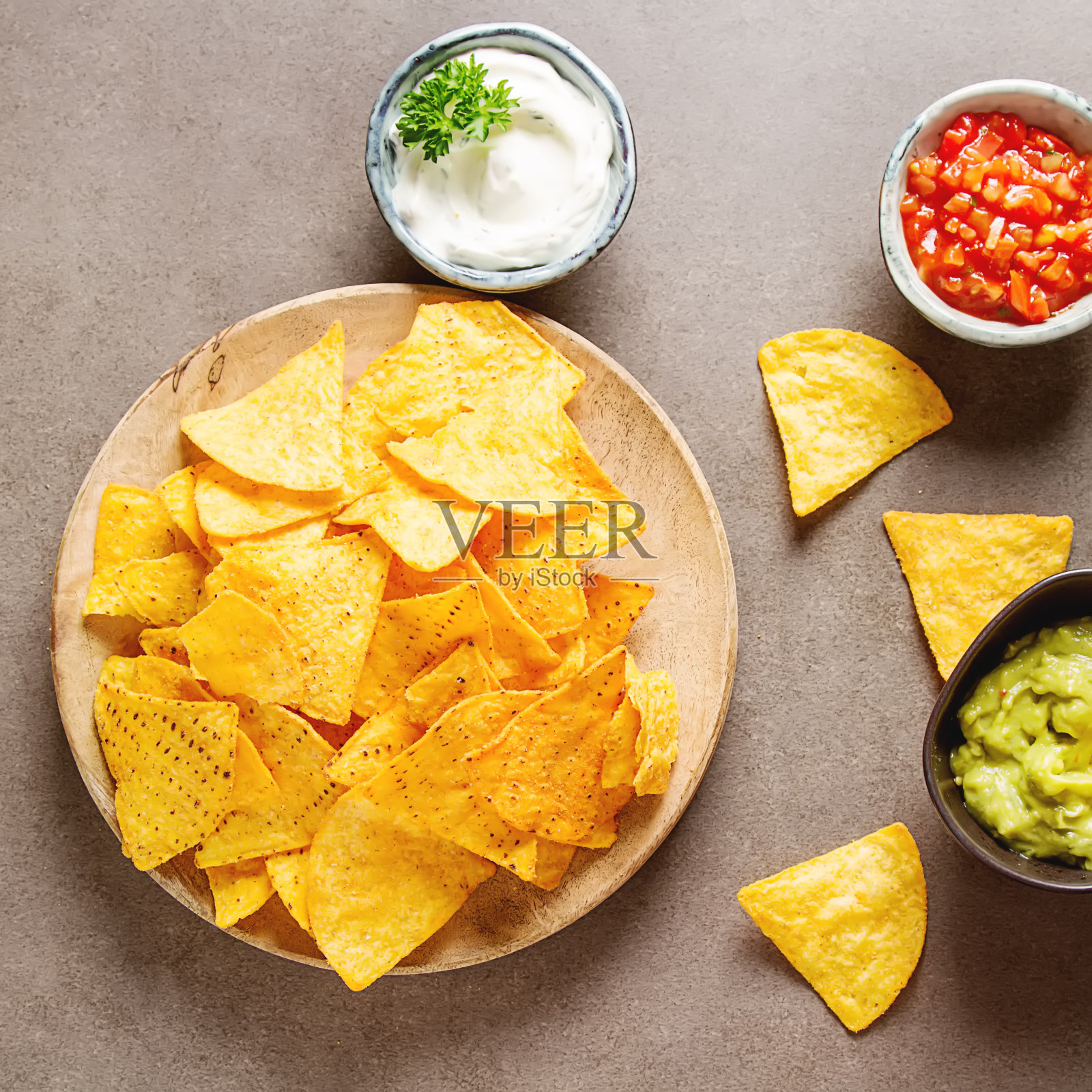 派对上的零食，玉米片配玉米饼，墨西哥玉米片配酱汁:莎莎酱配西红柿，酸奶油和鳄梨酱。墨西哥食物。黑暗的背景。前视图。本空间照片摄影图片